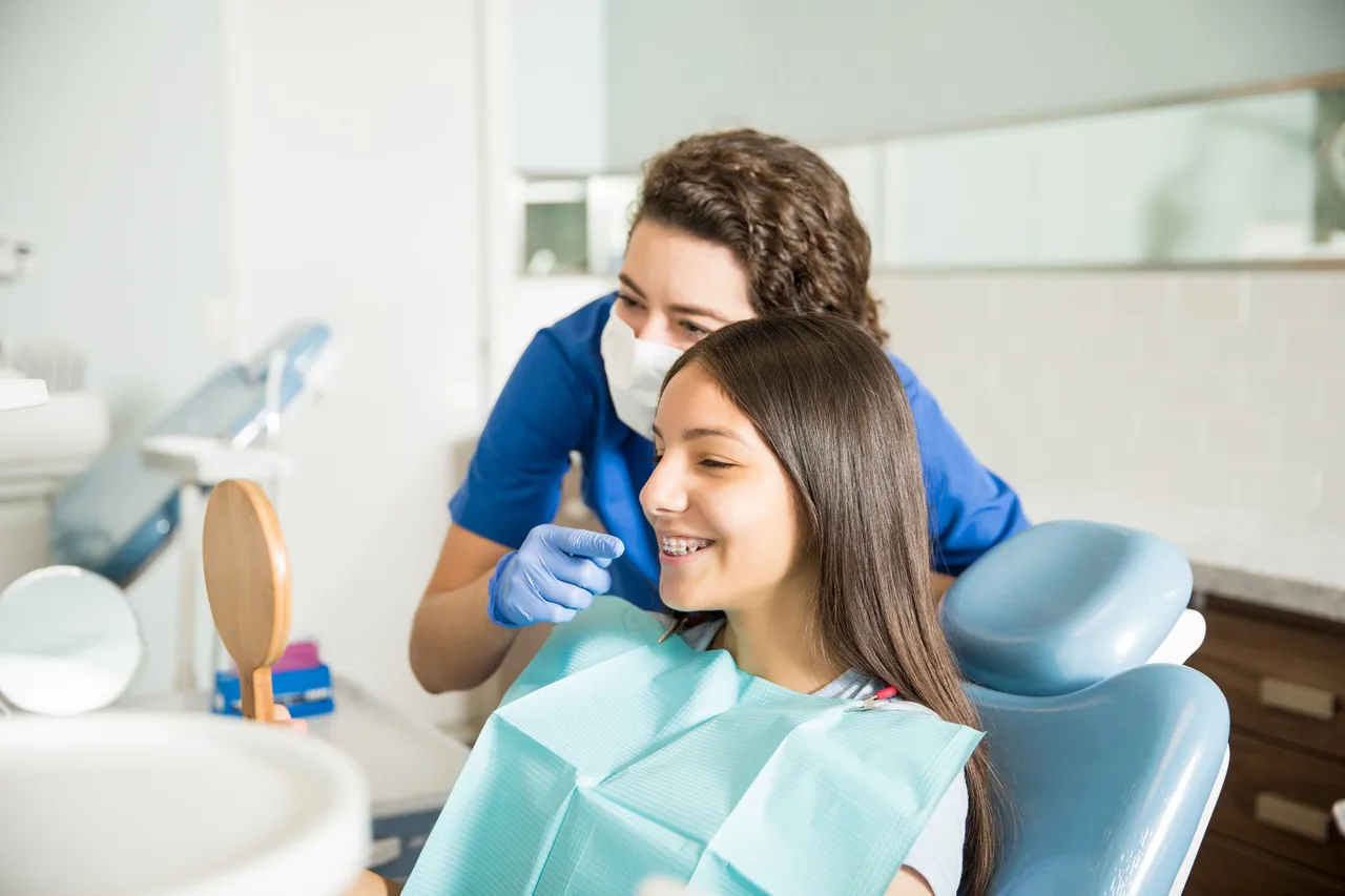 A clinician talking with a teenage patient in the chair