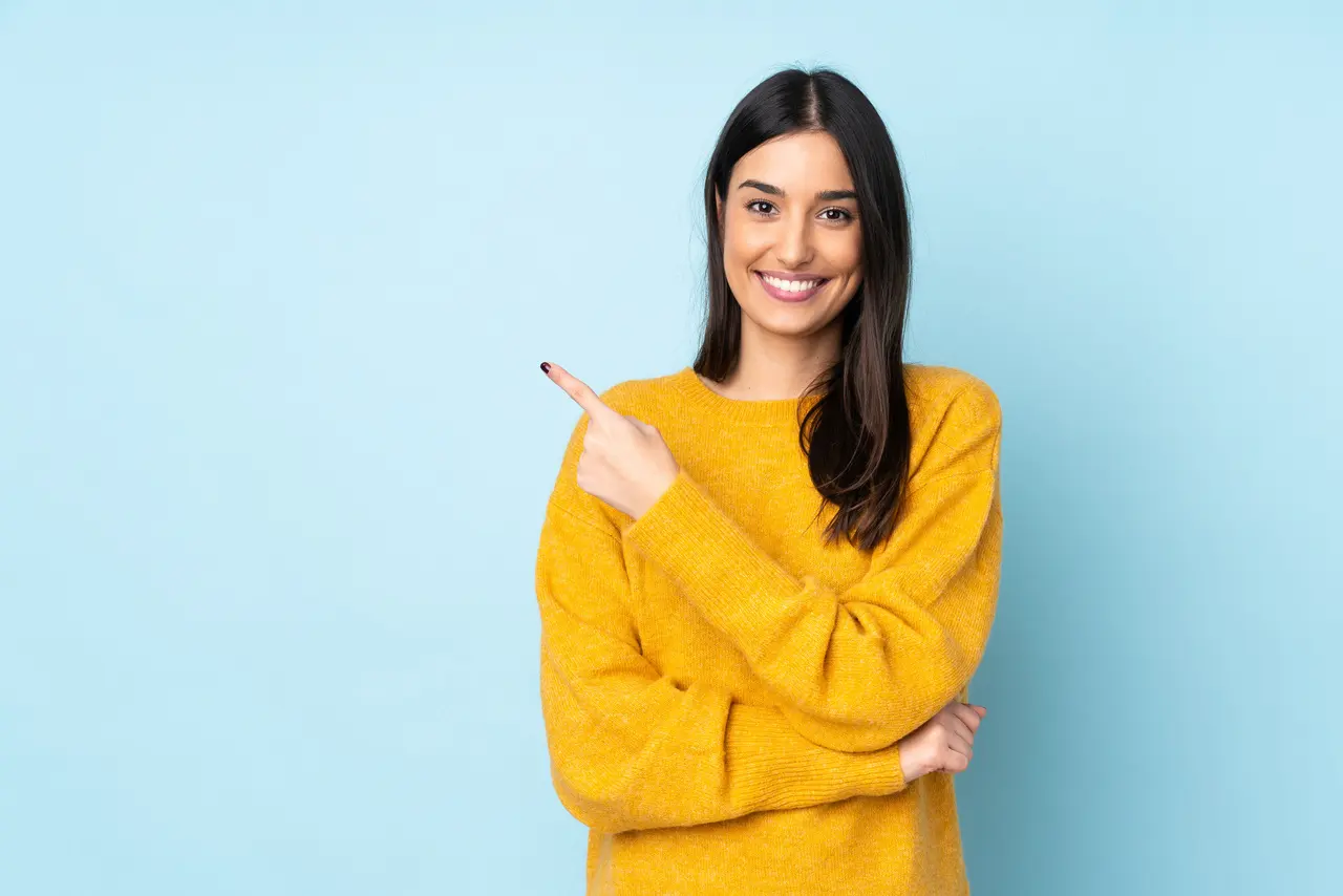 A woman pointing at her repaired, even smile