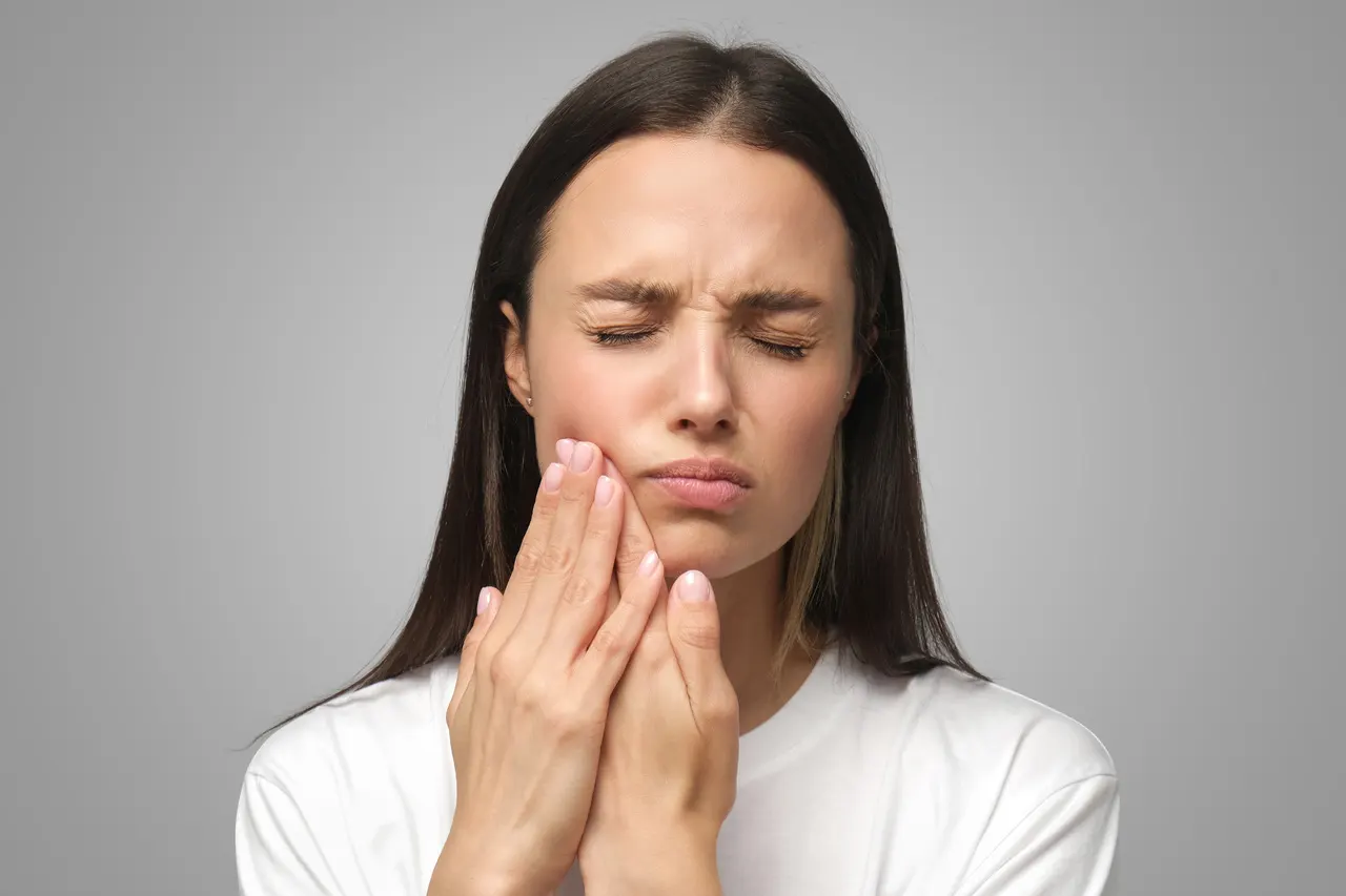 A woman holding her jaw in discomfort from a dental emergency