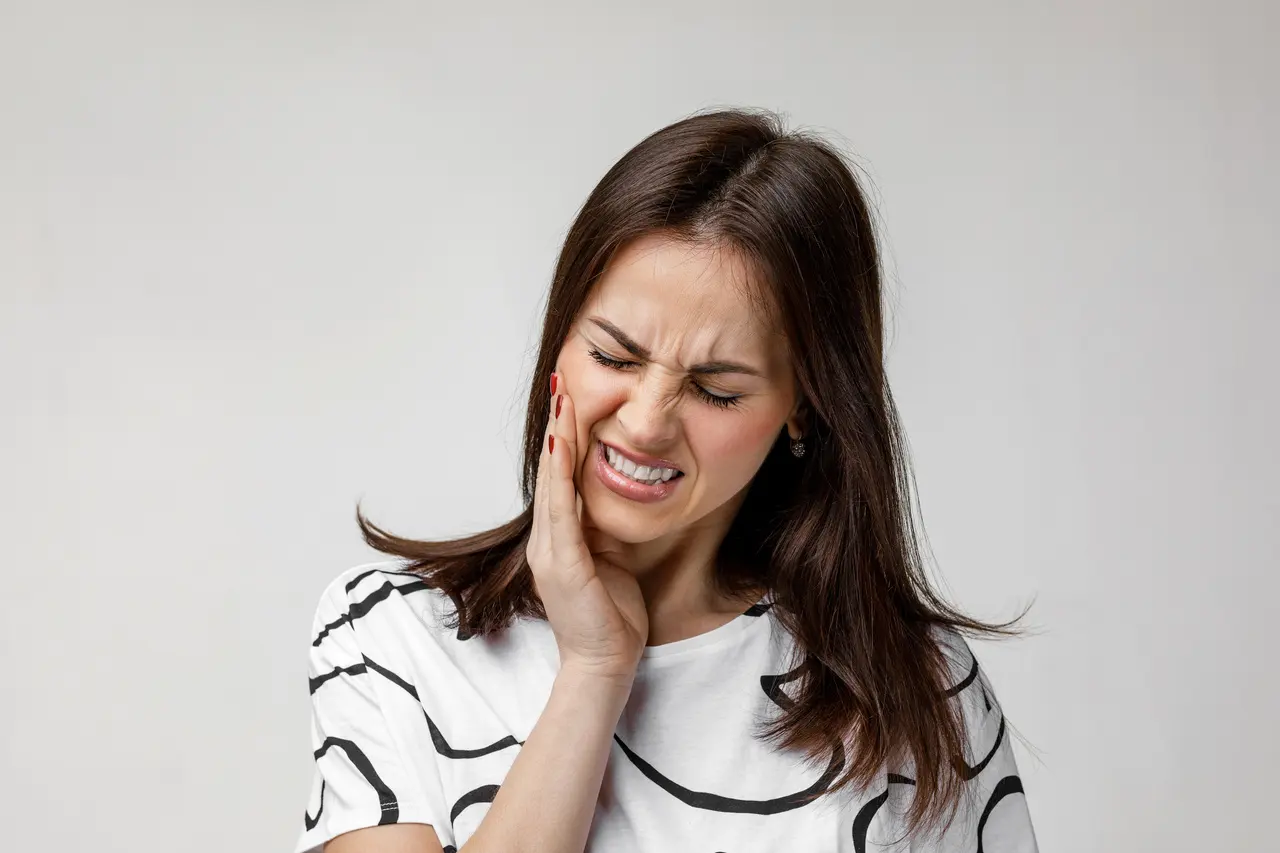 A woman holding her cheek because of tooth pain