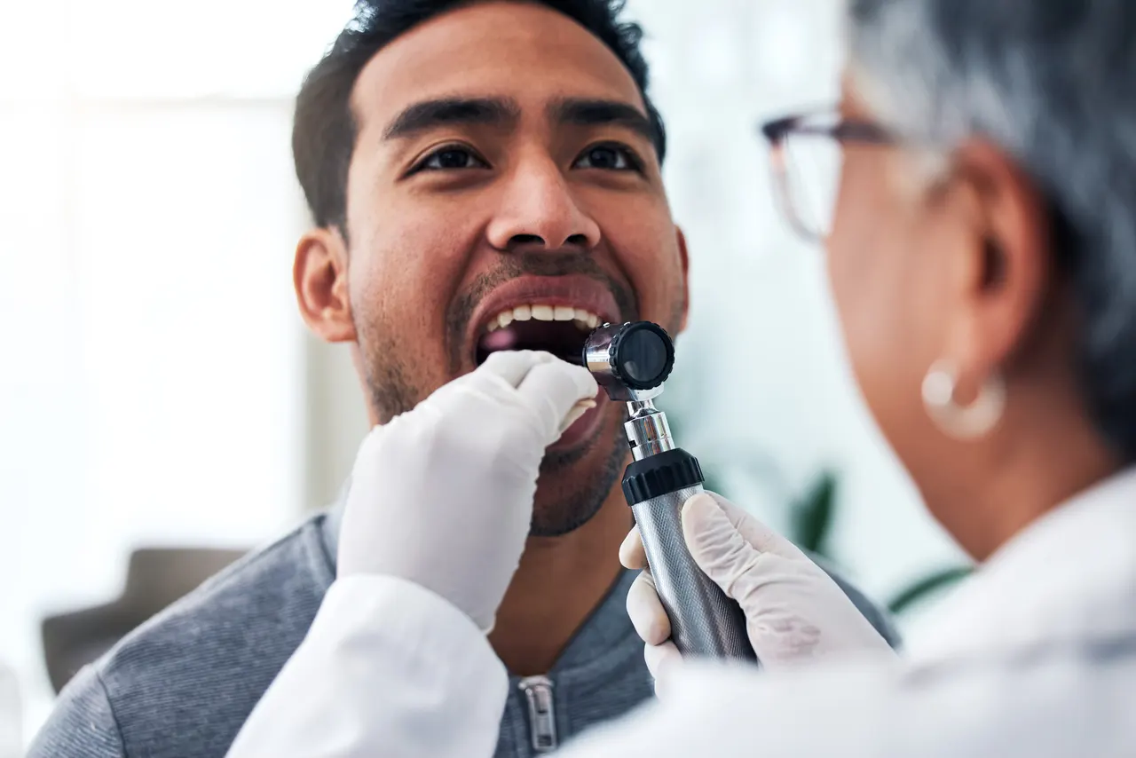 A dentist examining a patient's mouth with a light during a screening