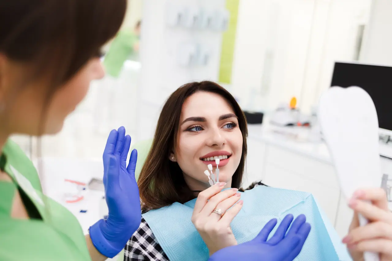 A dentist matching a veneer shade against a patient's smile