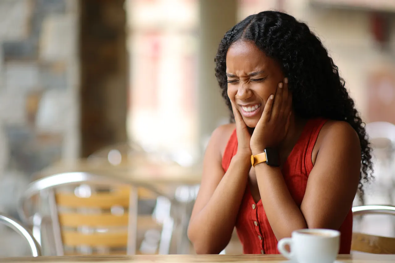 A woman holding her jaw in pain from TMJ discomfort